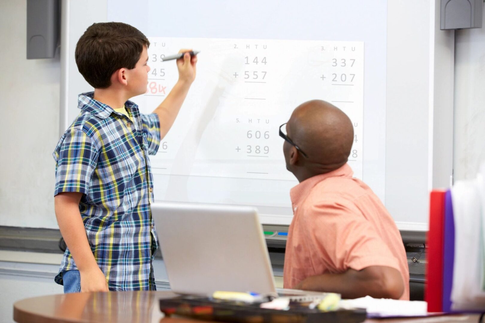 A boy and an adult are writing on the board