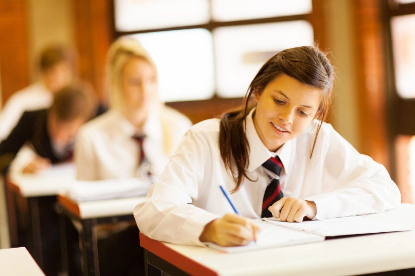 A girl in school uniform writing on paper.