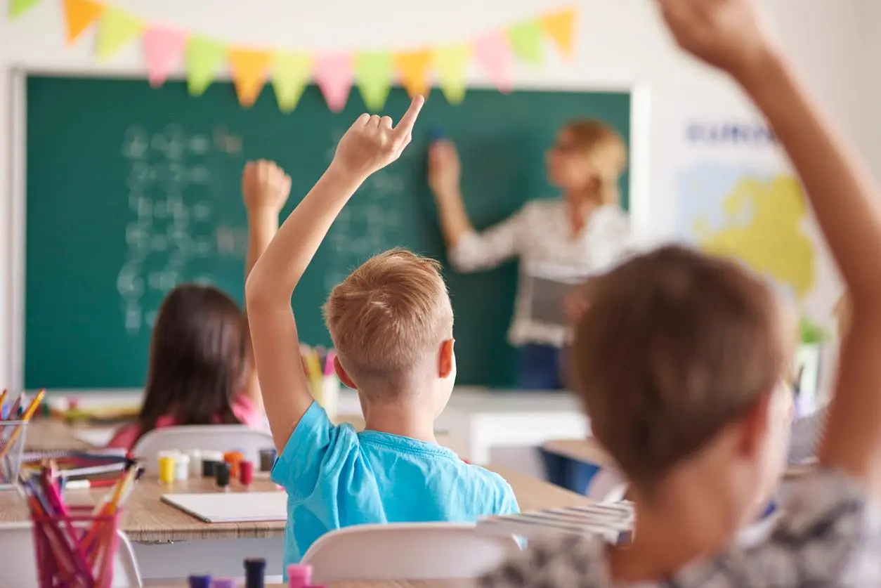 A boy raises his hand in front of an adult.